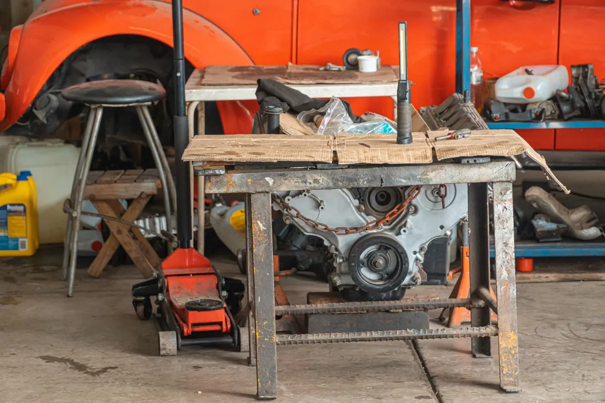 A cluttered garage workbench with an engine