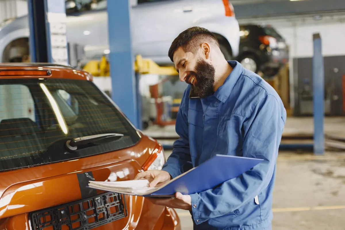 A mechanic reading a repair quote next to a car